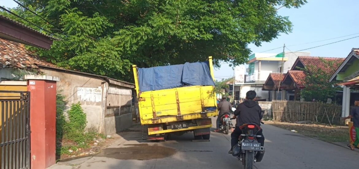 Sebuah truk jenis colt diesel bermuatan es batu balokan, diduga mengalami masalah pada bagian as roda ban belakang sebelah kirinya.