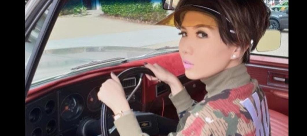 Ia mengenakan baju seperti sweater dengan motif loreng. Foto kedua Natalia Rusli dengan pakaian yang sama berpose diatas mobil Chevrolet.